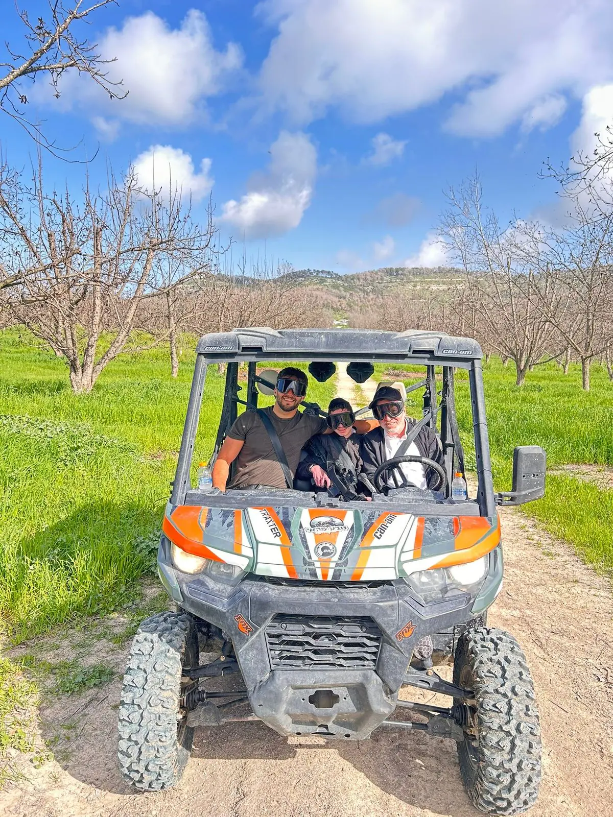 A family riding together through a green orchard